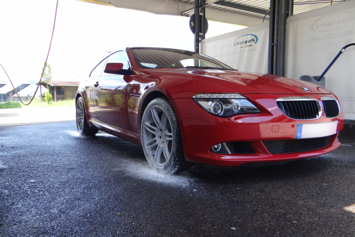 Roter BMW steht mit eingeseiften Felgen in einer Waschbox bei Kochwäsche